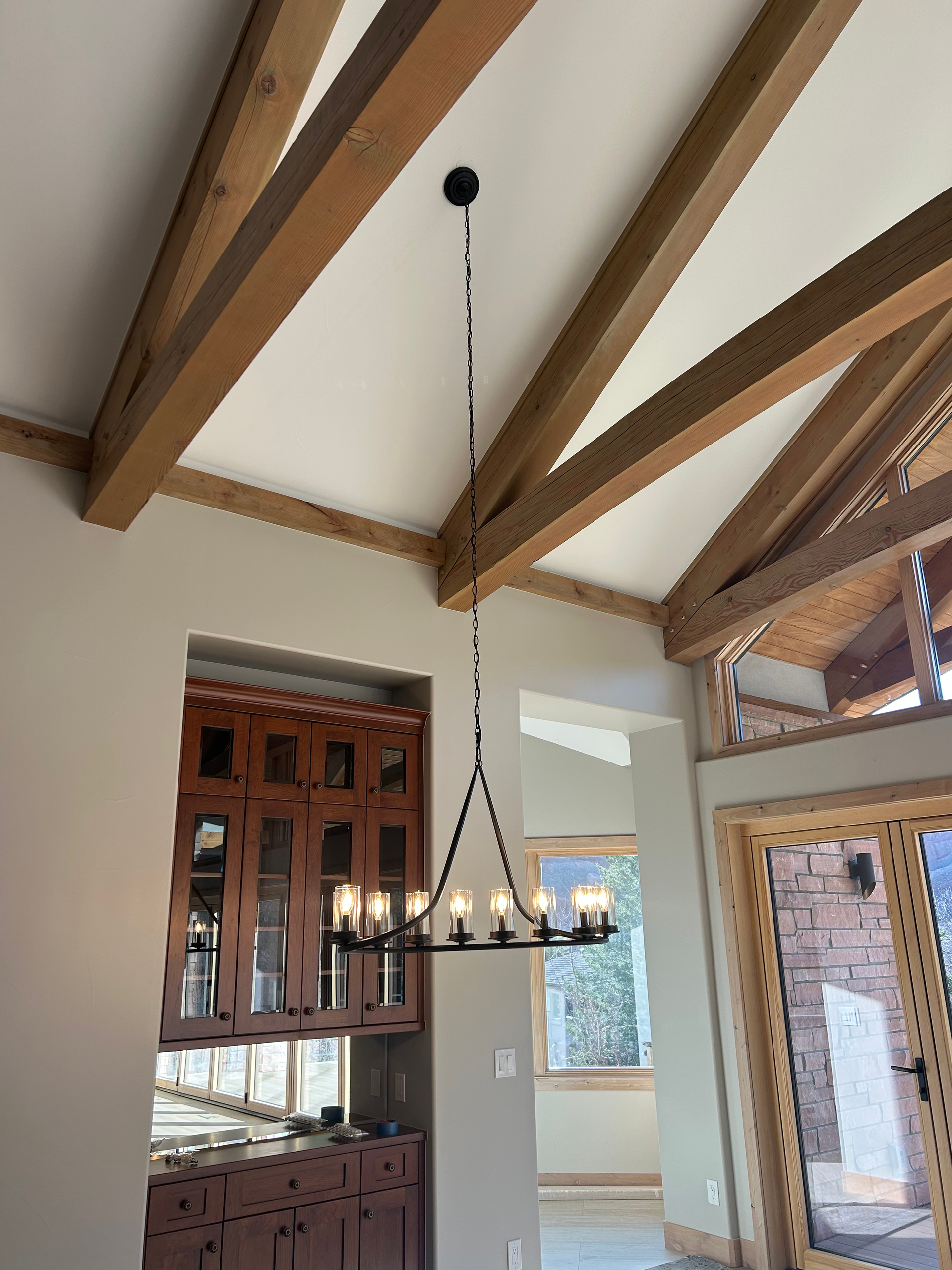 Dining room with wood beams, a black chandelier, and built-in cabinetry.