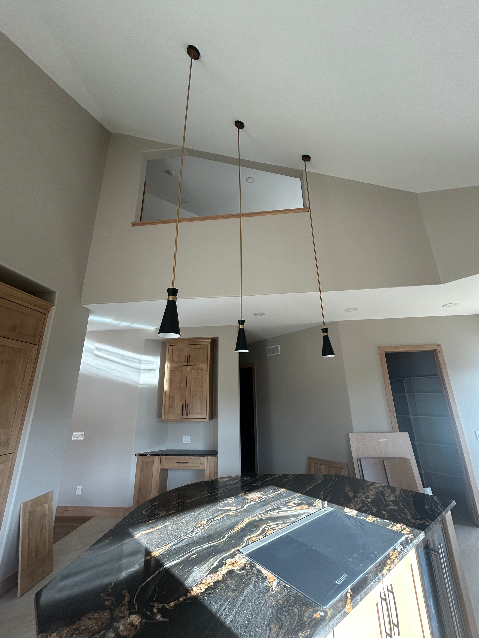 Kitchen with black granite countertop, pendant lights, cabinets, and an open doorway.