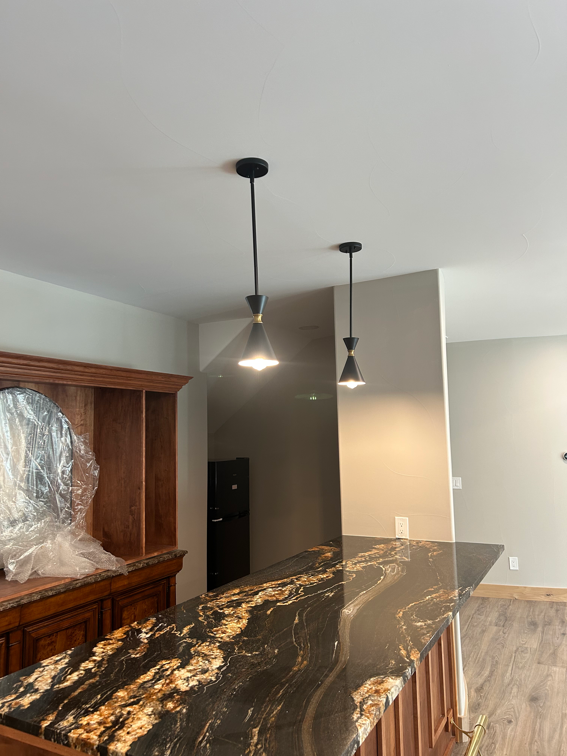 Two black pendant lights hang over a granite countertop bar.