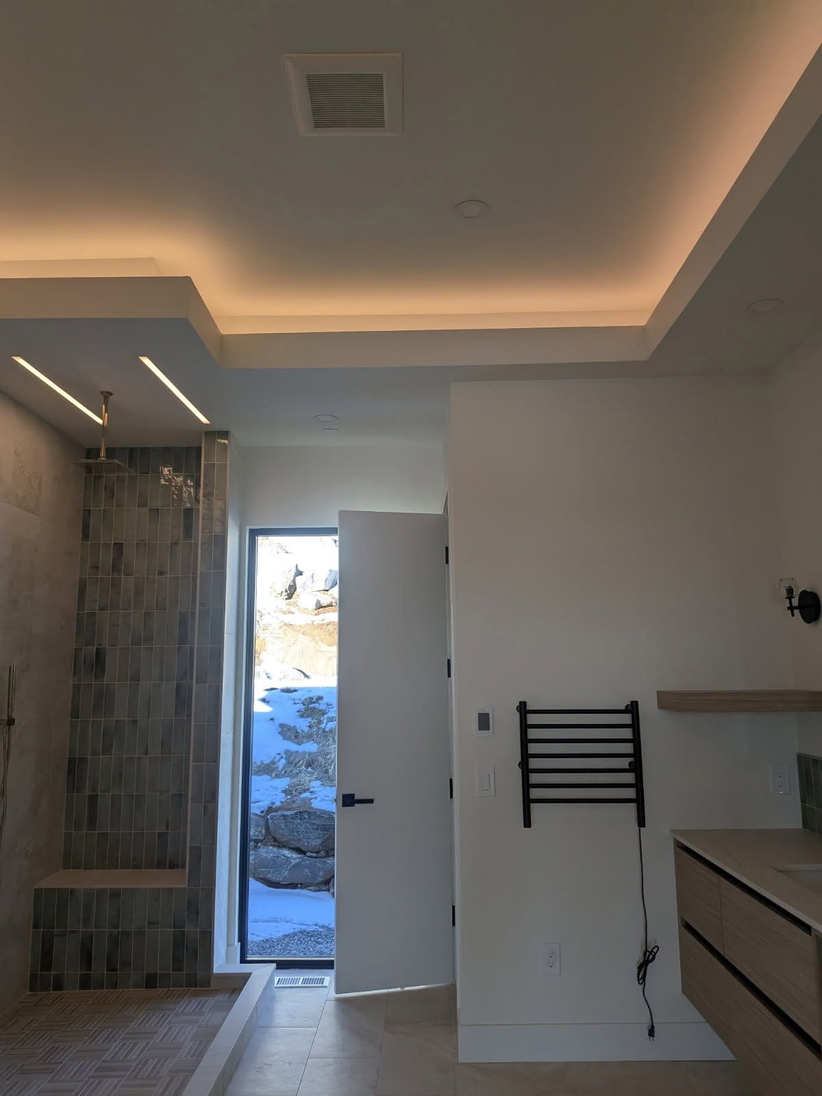Modern bathroom with shower, open doorway to snowy landscape, and ceiling lighting.