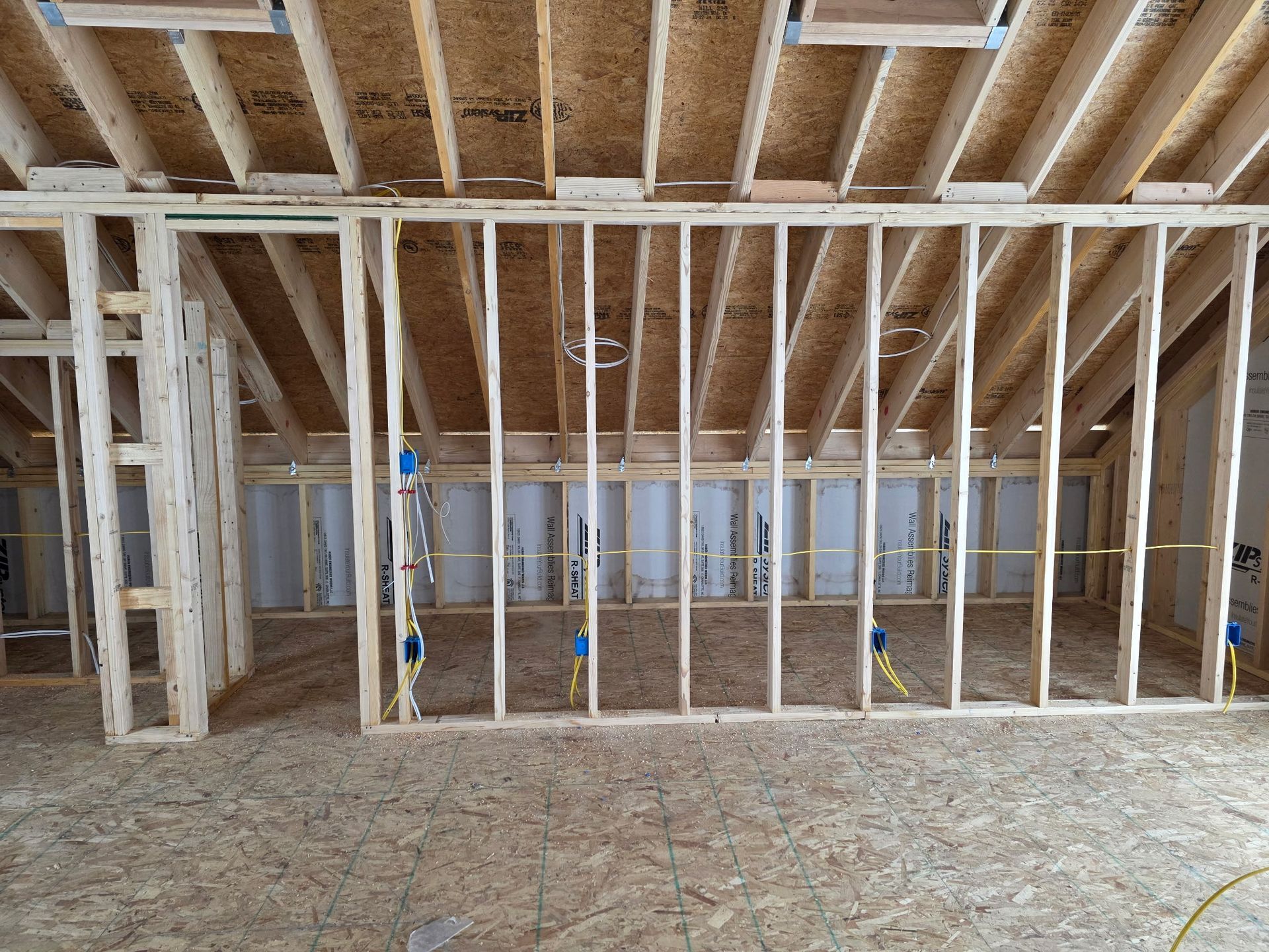 Interior framing of a room under construction with visible studs, wiring, and insulation.