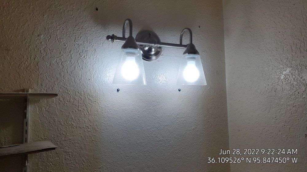 A light fixture is hanging on a wall in a bathroom.