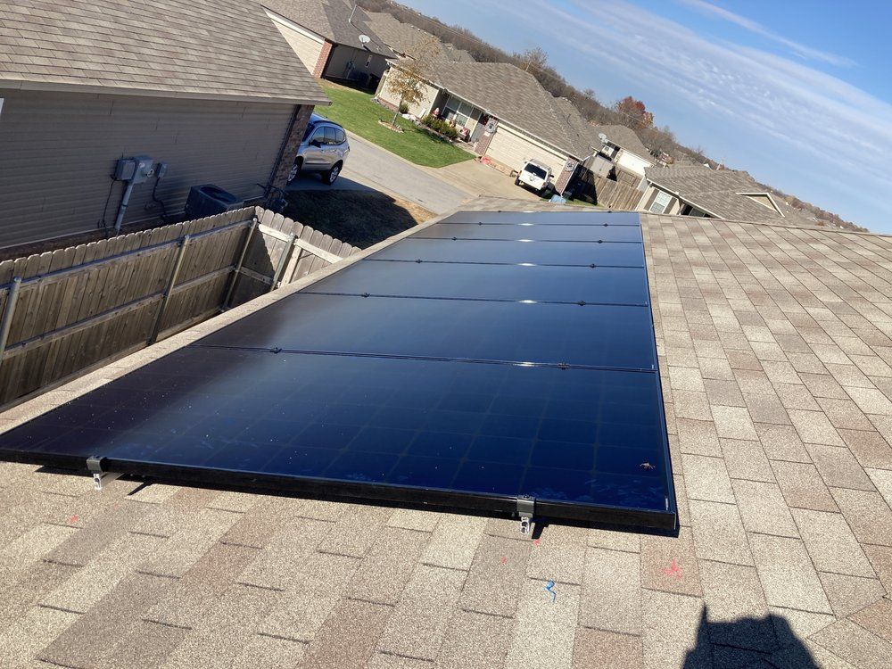 There are many solar panels on the roof of a house.