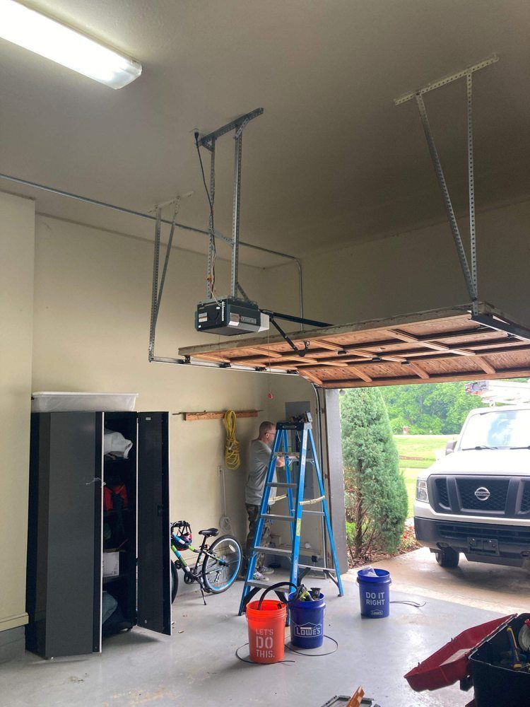 A man is working on a garage door opener in a garage.