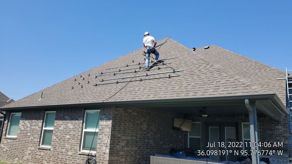 A man is standing on the roof of a house.