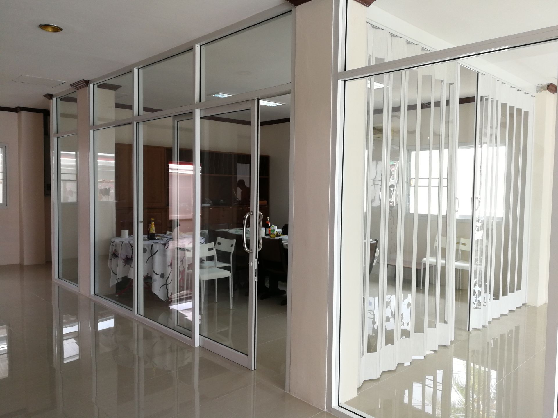 Interior with white and glass room dividers, a tiled floor, and a dining area.