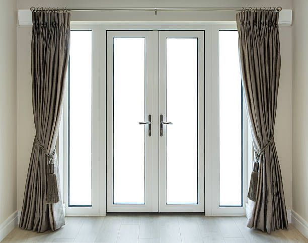 White French doors and sidelights with gray curtains tied back.
