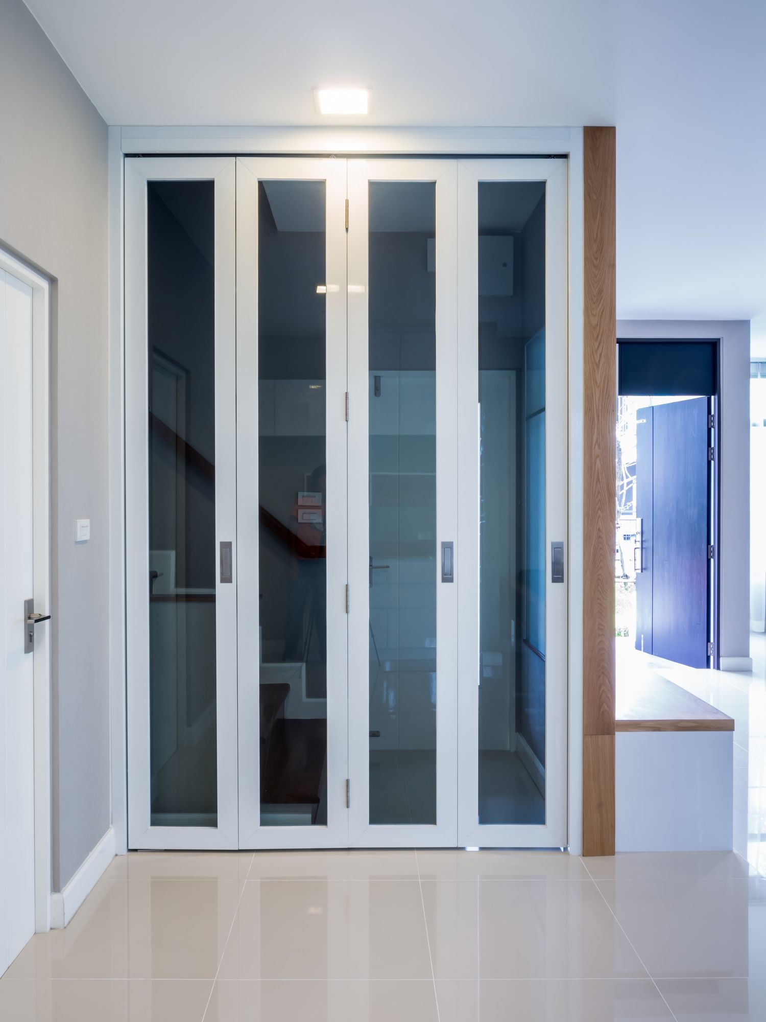 White folding glass doors enclose a small room. The floor is tiled.