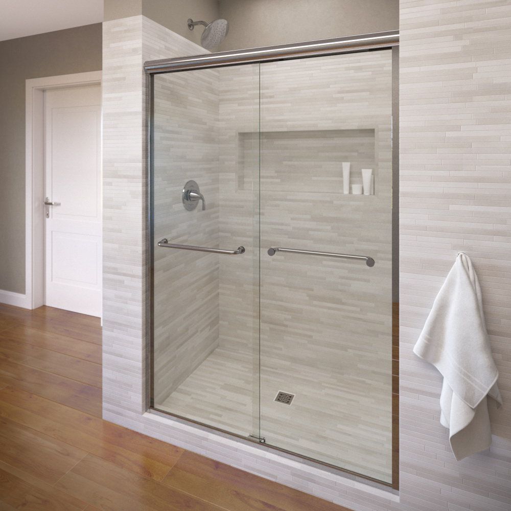 Shower with sliding glass doors, chrome hardware, built-in shelf, white tiled walls, and towel.