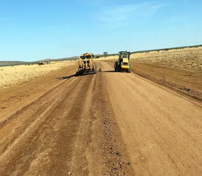 Two construction vehicles grading a dirt road under a blue sky — Lamont Civil Services Pty Ltd In Townview, QLD