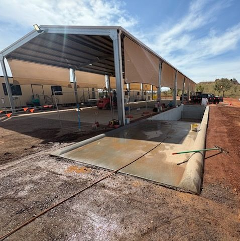 Outdoor vehicle wash bay under a metal roof with shade cloth. Concrete pad, dusty ground, sunny day.  - Lamont , Cloncurry, QLD.