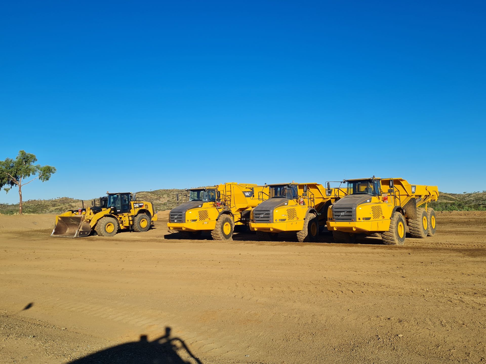 Road grading: a yellow bulldozer and skid steer compacting and leveling a dirt road under a blue sky. — Lamont Civil Services Pty Ltd In Townview, QLD