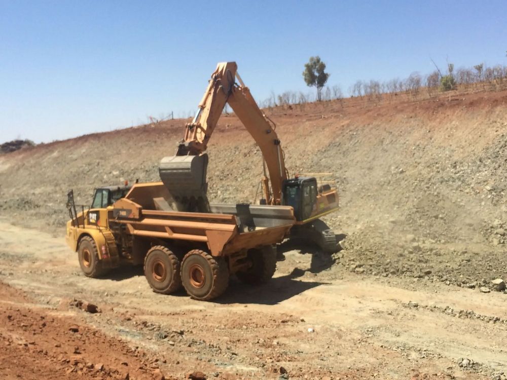 Yellow Excavator Loading a Yellow Dump Truck at a Construction Site — Lamont Civil Services Pty Ltd In Townview, QLD