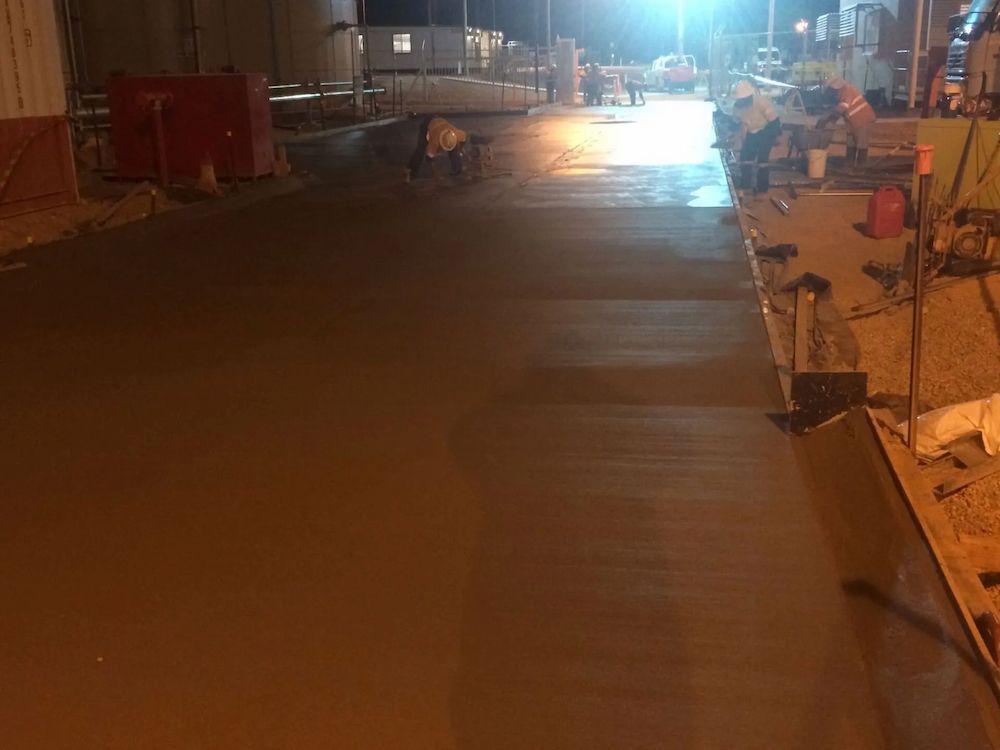Workers Smoothing Wet Concrete on a Road at Night — Lamont Civil Services Pty Ltd In Mount Isa, QLD