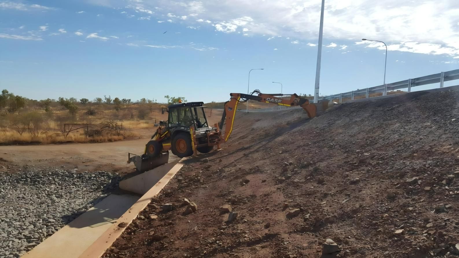 Backhoe Excavator Working on a Slope Near a Road and Guardrail — Lamont Civil Services Pty Ltd In Townview, QLD