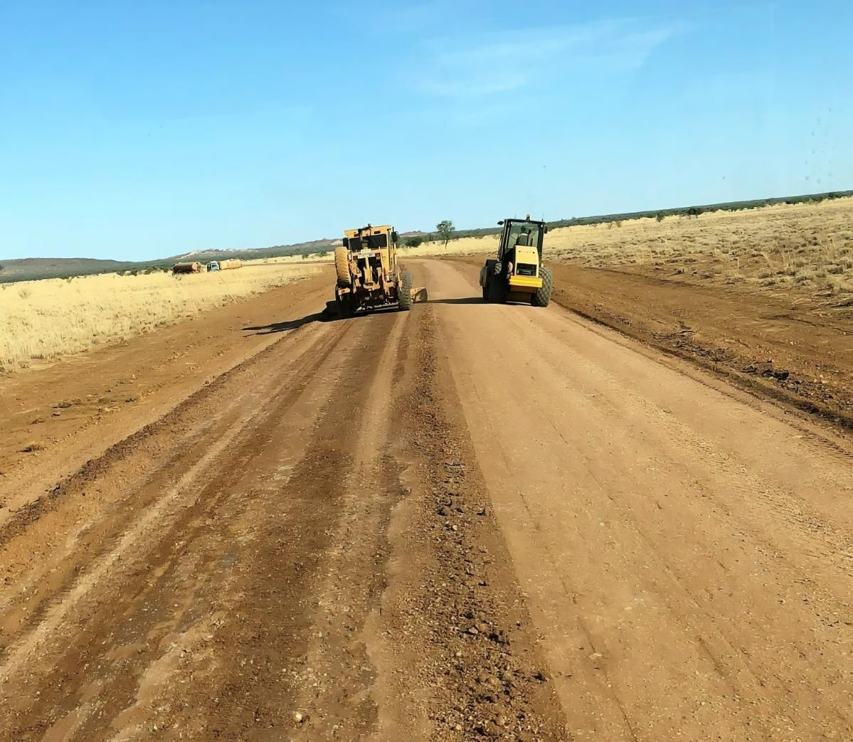 Grading Road With Heavy Machinery on a Dirt Road Under a Blue Sky — Lamont Civil Services Pty Ltd In Townview, QLD