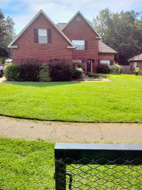 A large brick house with a lush green lawn in front of it.