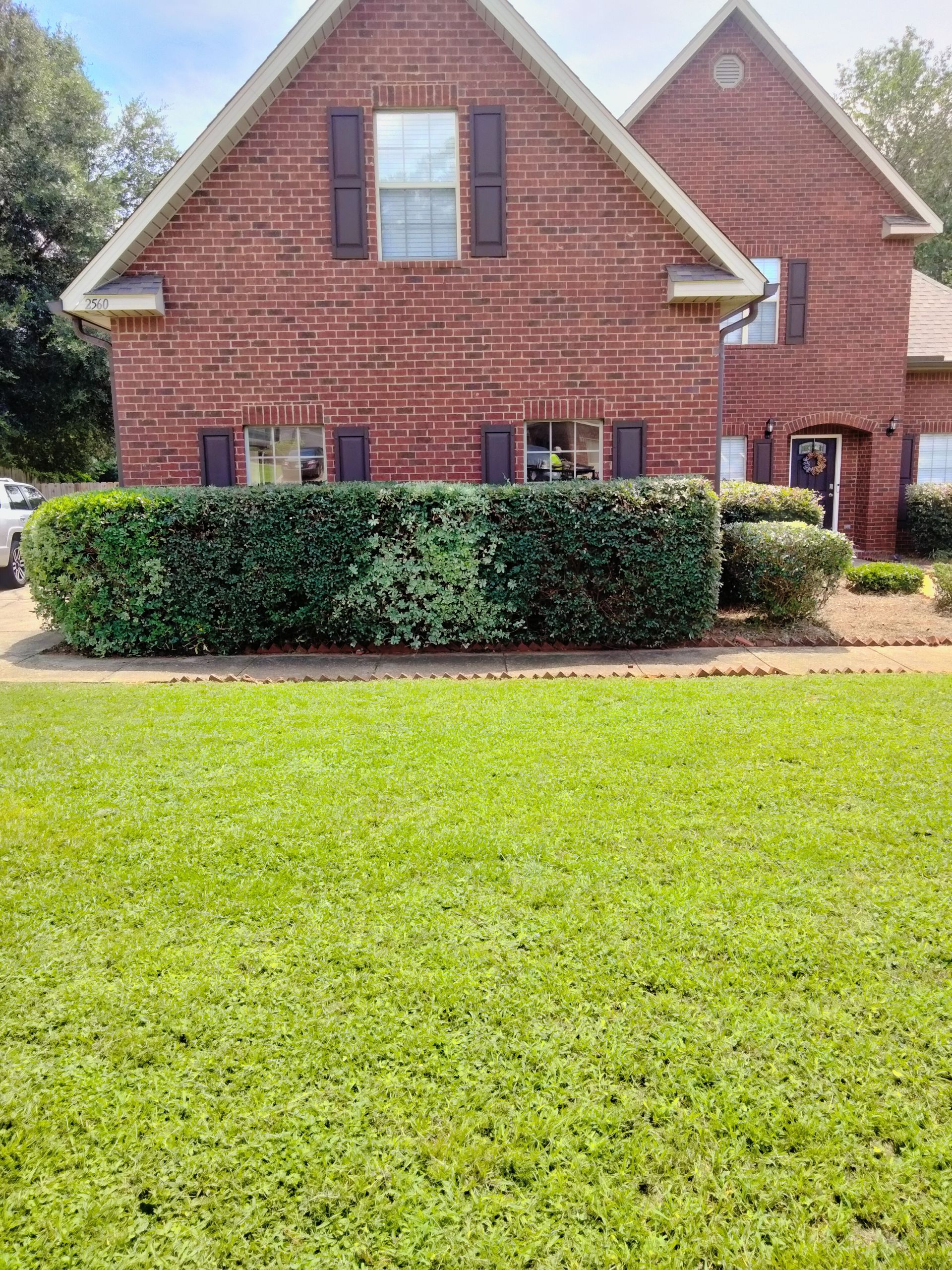 A large brick house with a lush green lawn in front of it.
