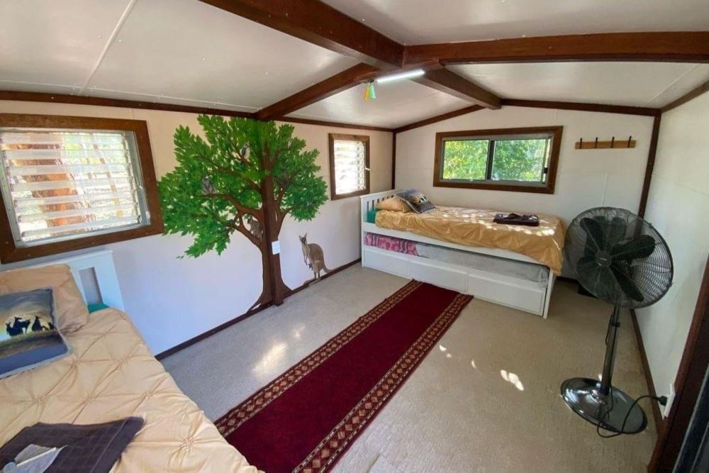 A Bedroom With Two Beds, a Fan and a Tree on the Wall — Nina's Ark Wildlife Sanctuary In Finniss Valley, NT