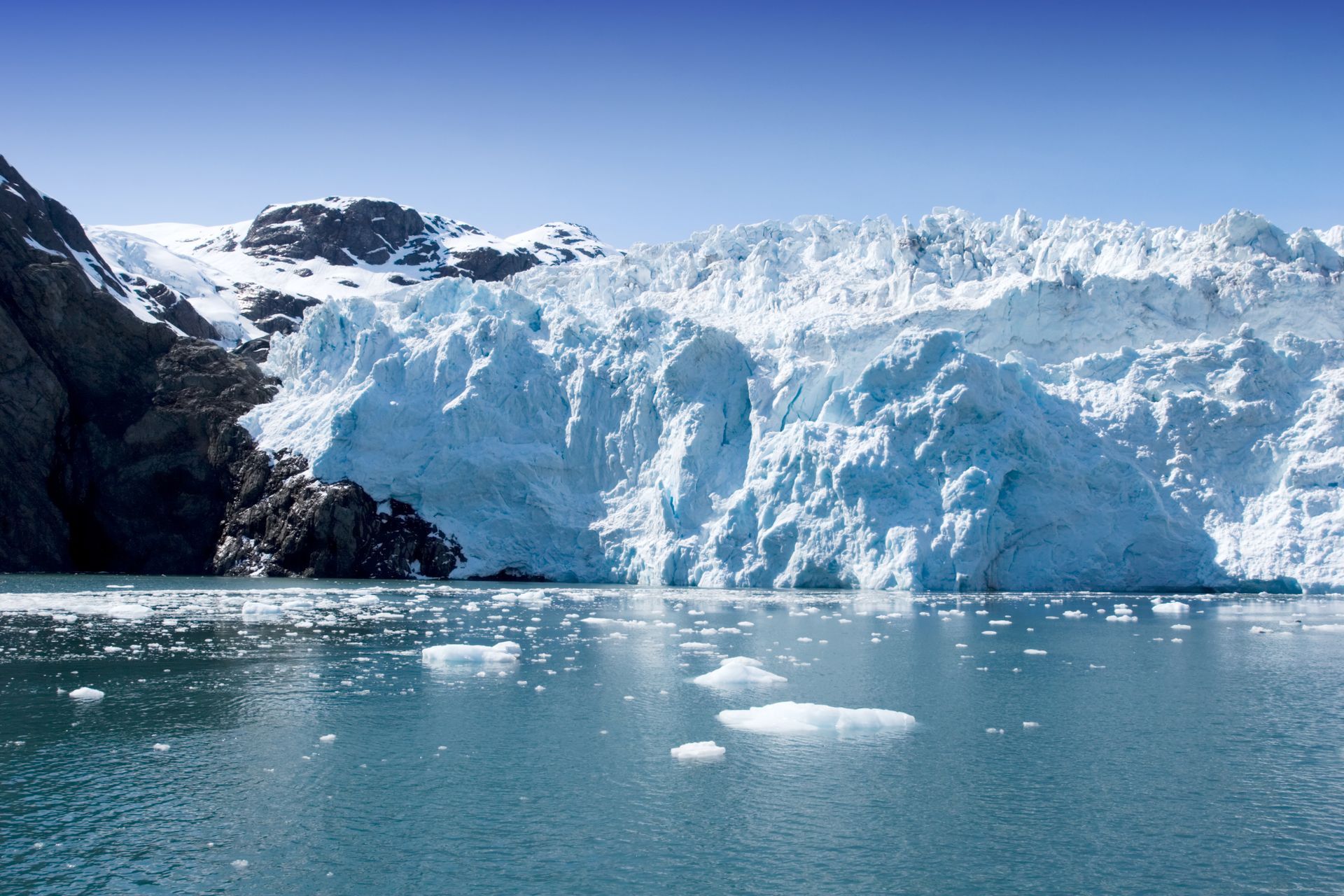 Alaskan glacier with icy blue peaks and mountain backdrop