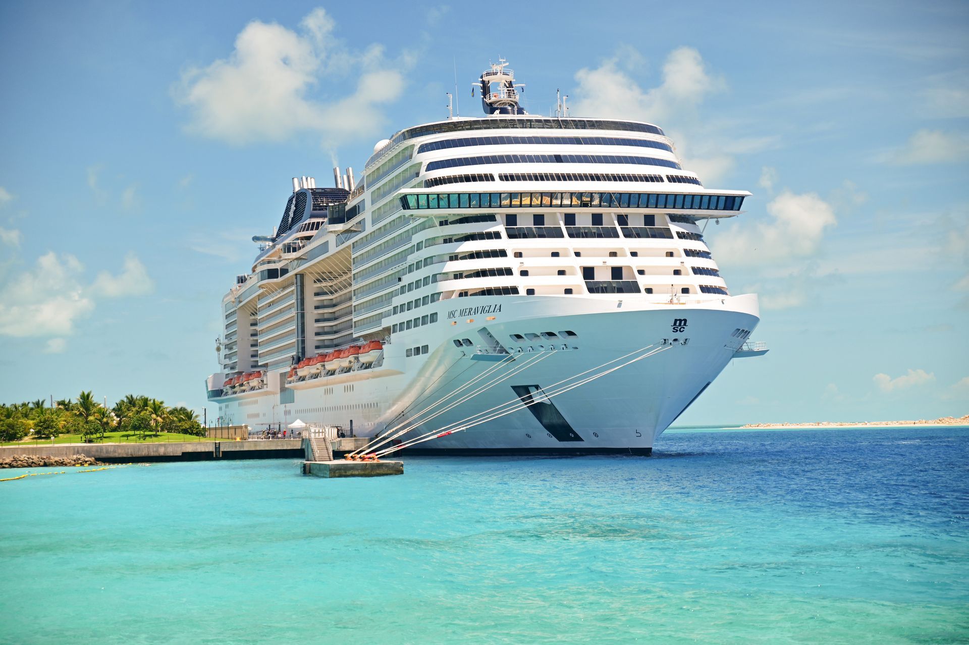 Spacious modern living room with dining area, beige and gray tones, large windows, and a colorful rug.