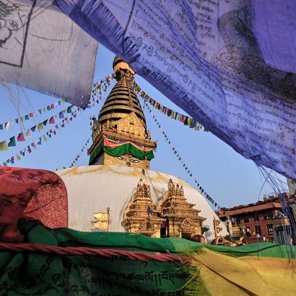 Golden stupa at Swayambhunath temple in Kathmandu, Nepal, with colorful prayer flags under a blue sky.