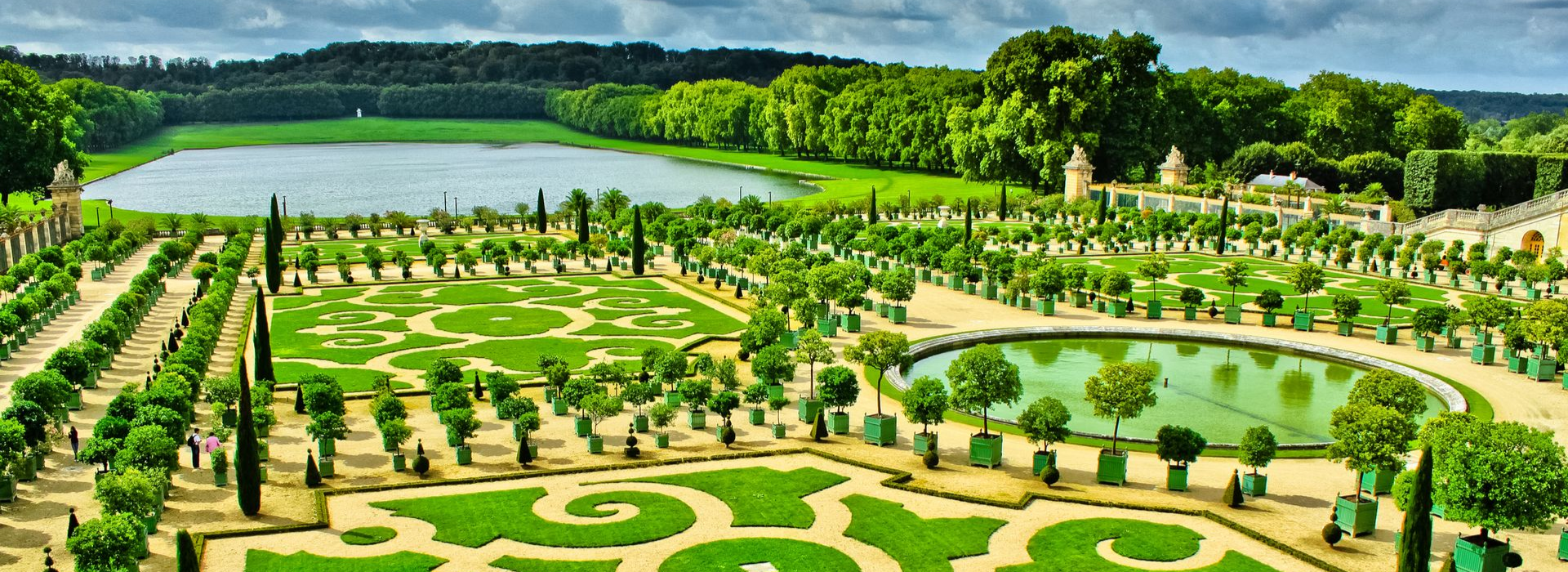 Spacious modern living room with dining area, beige and gray tones, large windows, and a colorful rug.