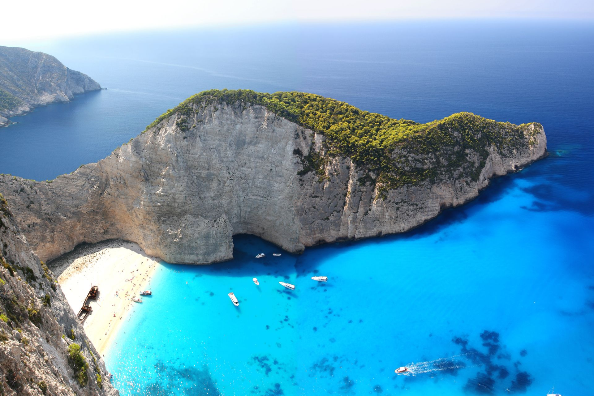 Spacious modern living room with dining area, beige and gray tones, large windows, and a colorful rug.