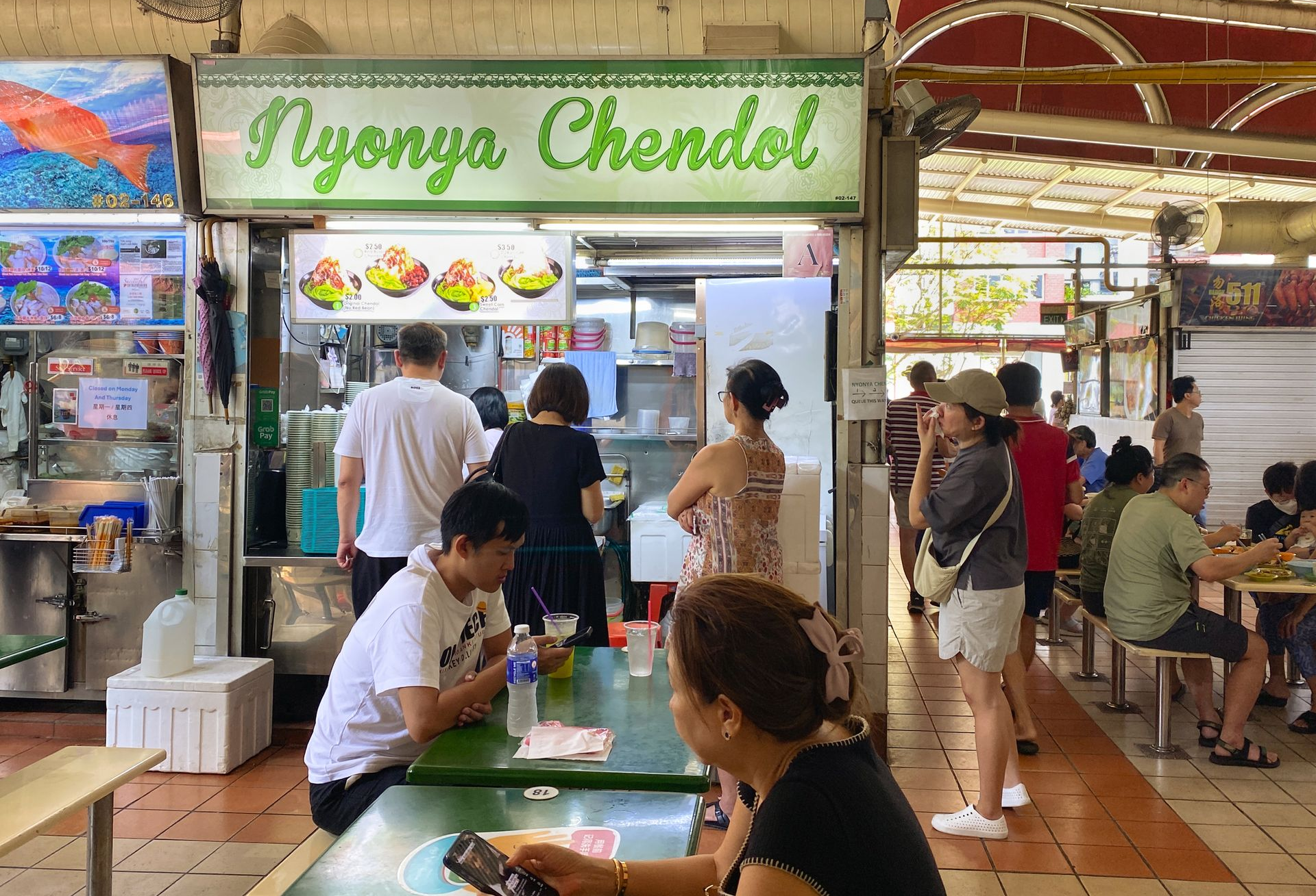 Spacious modern living room with dining area, beige and gray tones, large windows, and a colorful rug.
