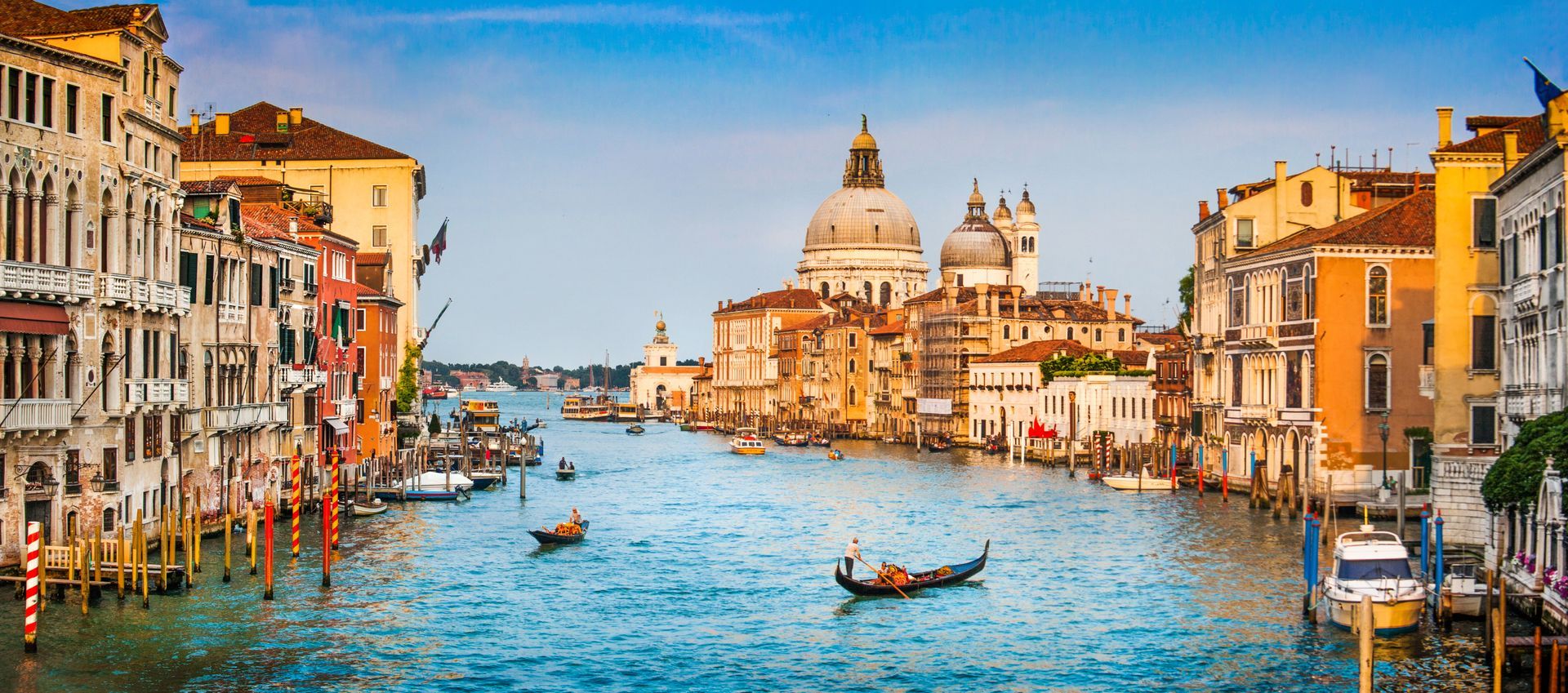 Venice canal with gondolas and Santa Maria della Salute under golden afternoon light.