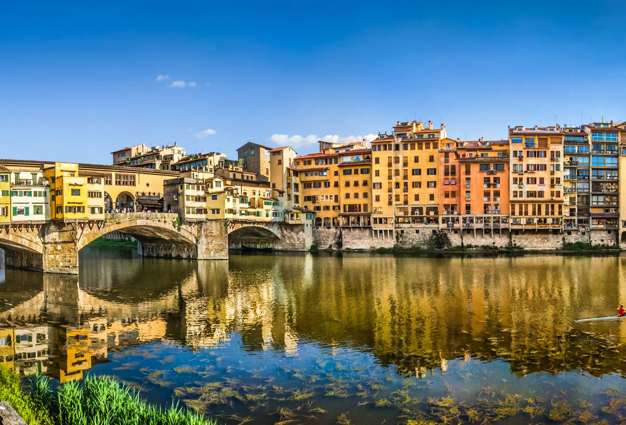 Spacious modern living room with dining area, beige and gray tones, large windows, and a colorful rug.