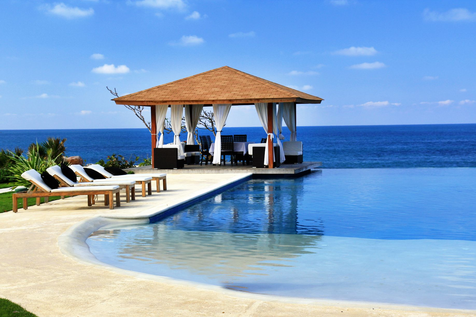 Spacious modern living room with dining area, beige and gray tones, large windows, and a colorful rug.