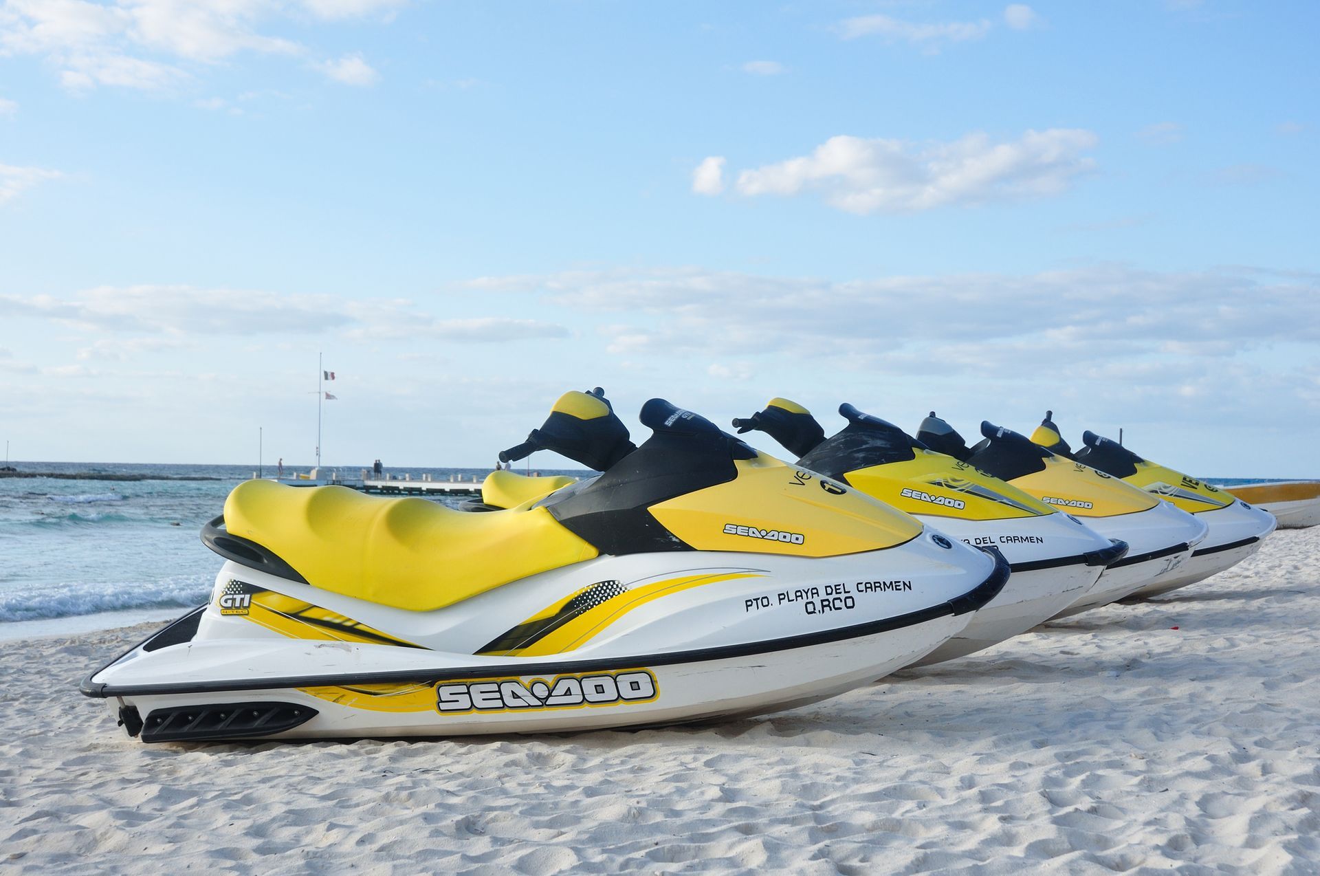 Jet skis lined up on tropical shoreline — water sports and adventure travel in Mexico.
