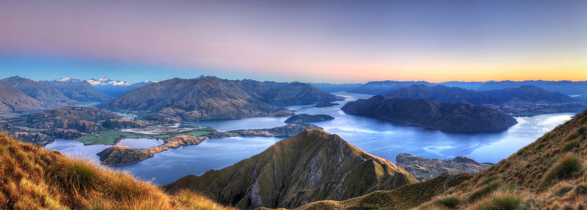 New Zealand landscape with lake, hills, and snow-capped peaks