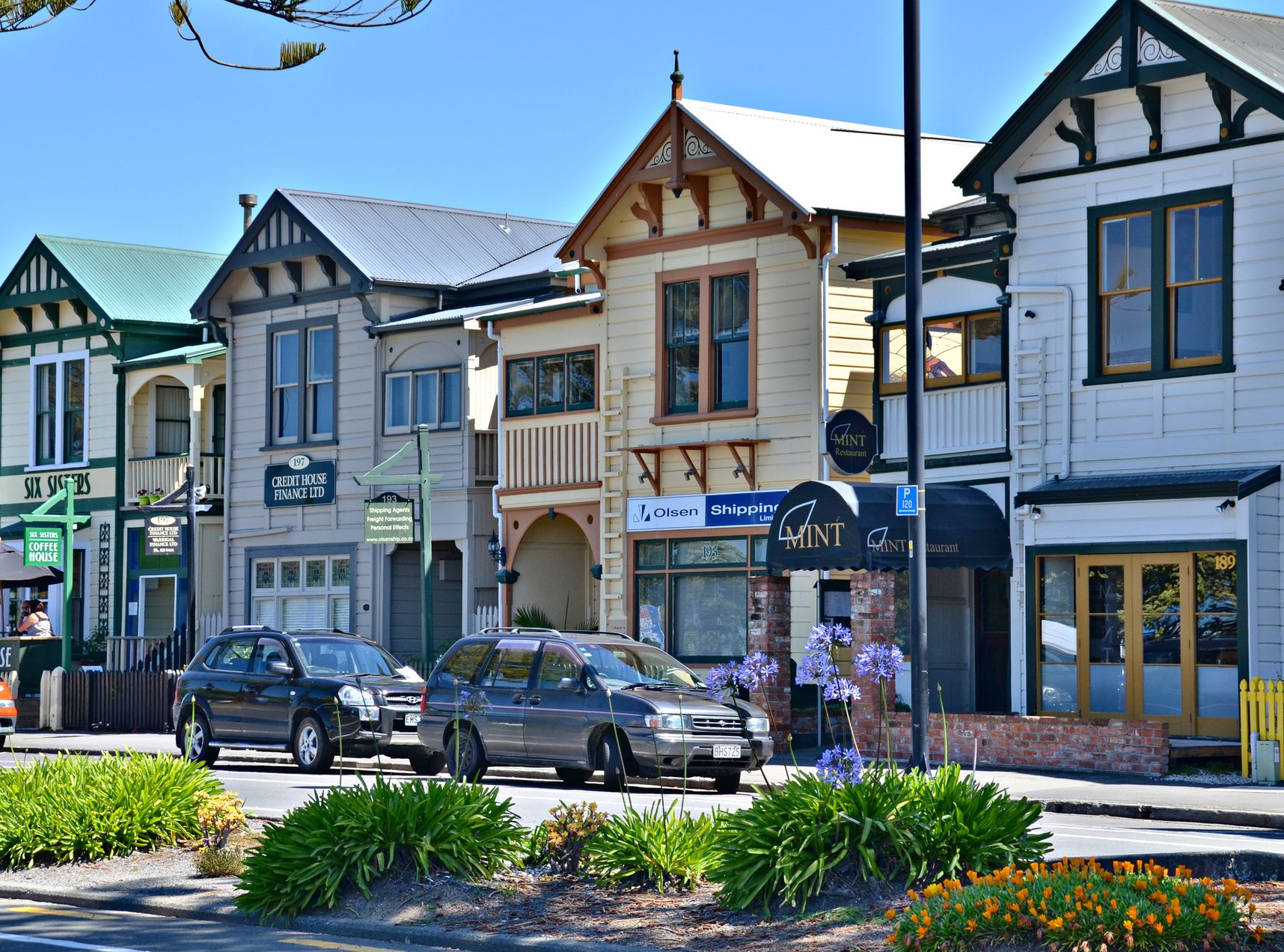 Spacious modern living room with dining area, beige and gray tones, large windows, and a colorful rug.