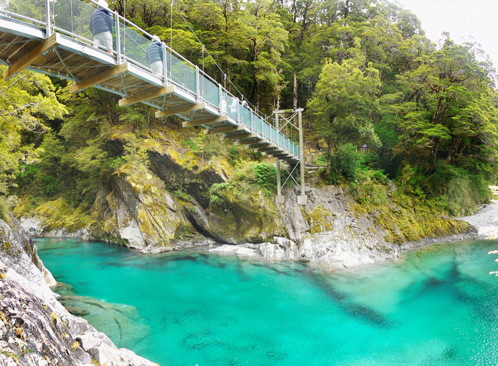 Spacious modern living room with dining area, beige and gray tones, large windows, and a colorful rug.