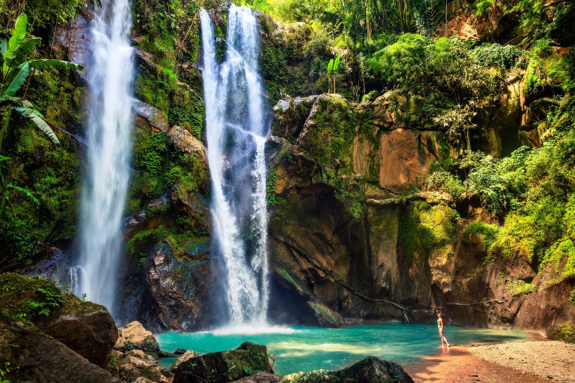 Spacious modern living room with dining area, beige and gray tones, large windows, and a colorful rug.