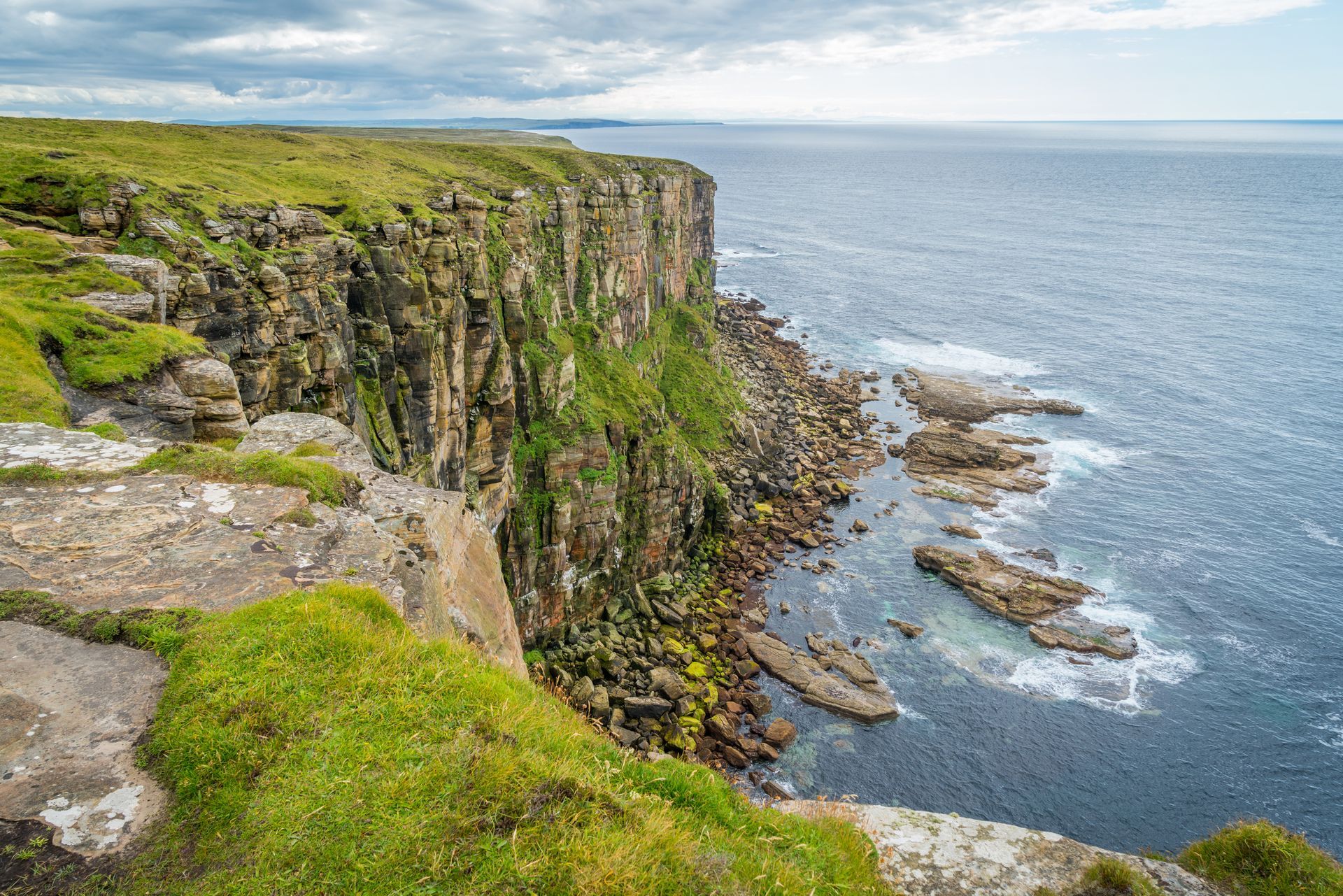 Spacious modern living room with dining area, beige and gray tones, large windows, and a colorful rug.