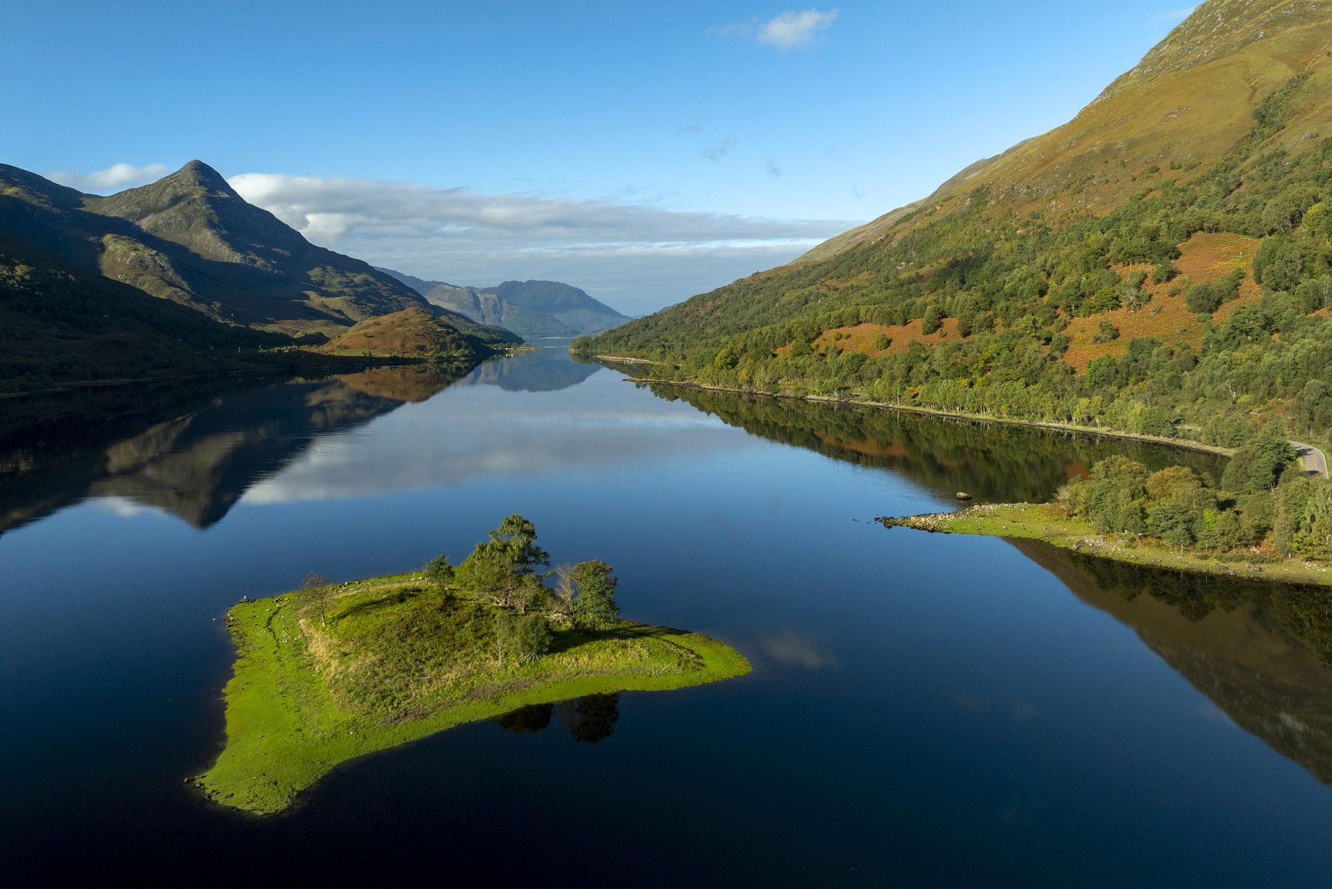 Spacious modern living room with dining area, beige and gray tones, large windows, and a colorful rug.