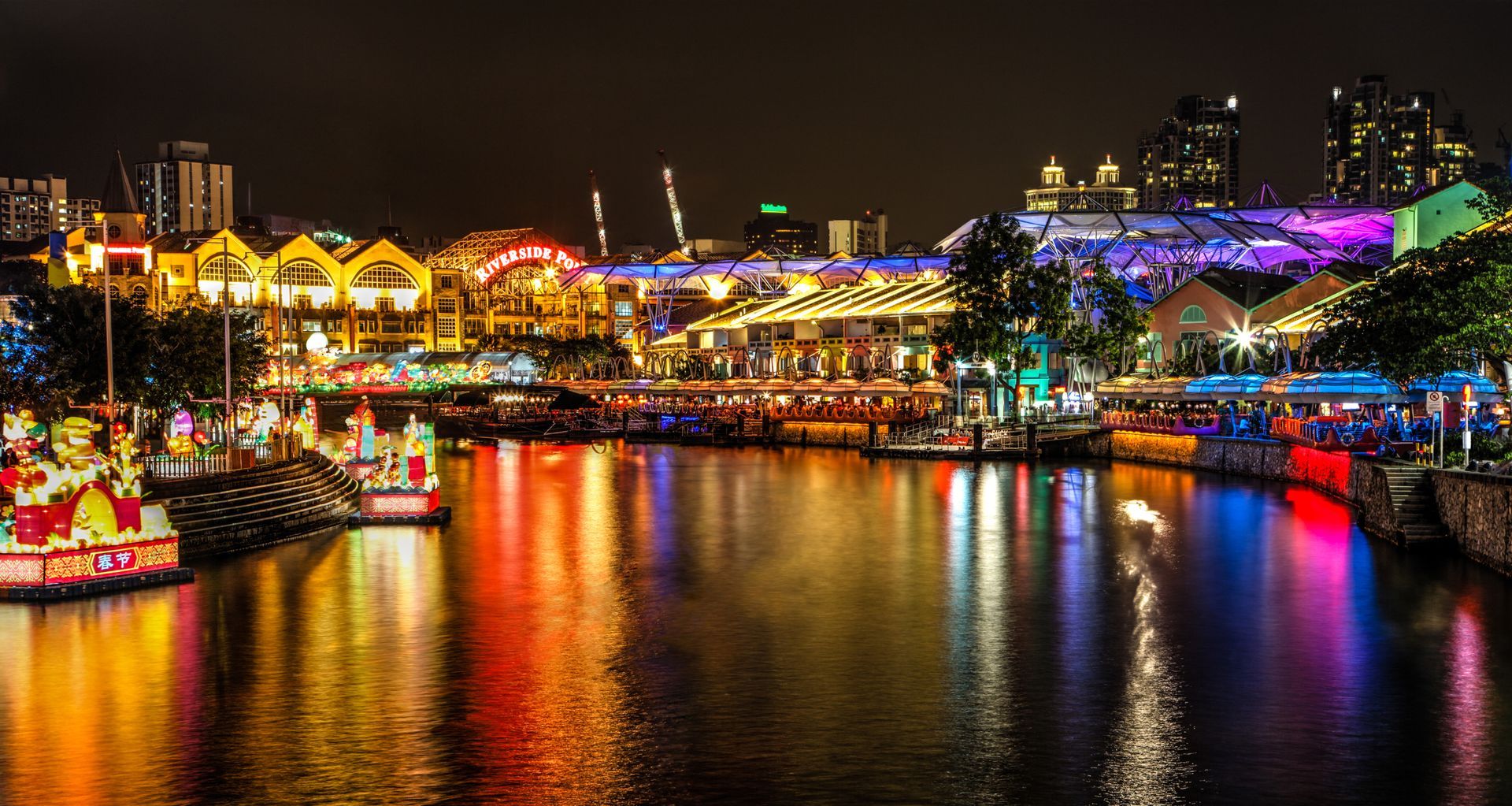 Night view of Singapore waterfront with colorful lights reflected in the water.
