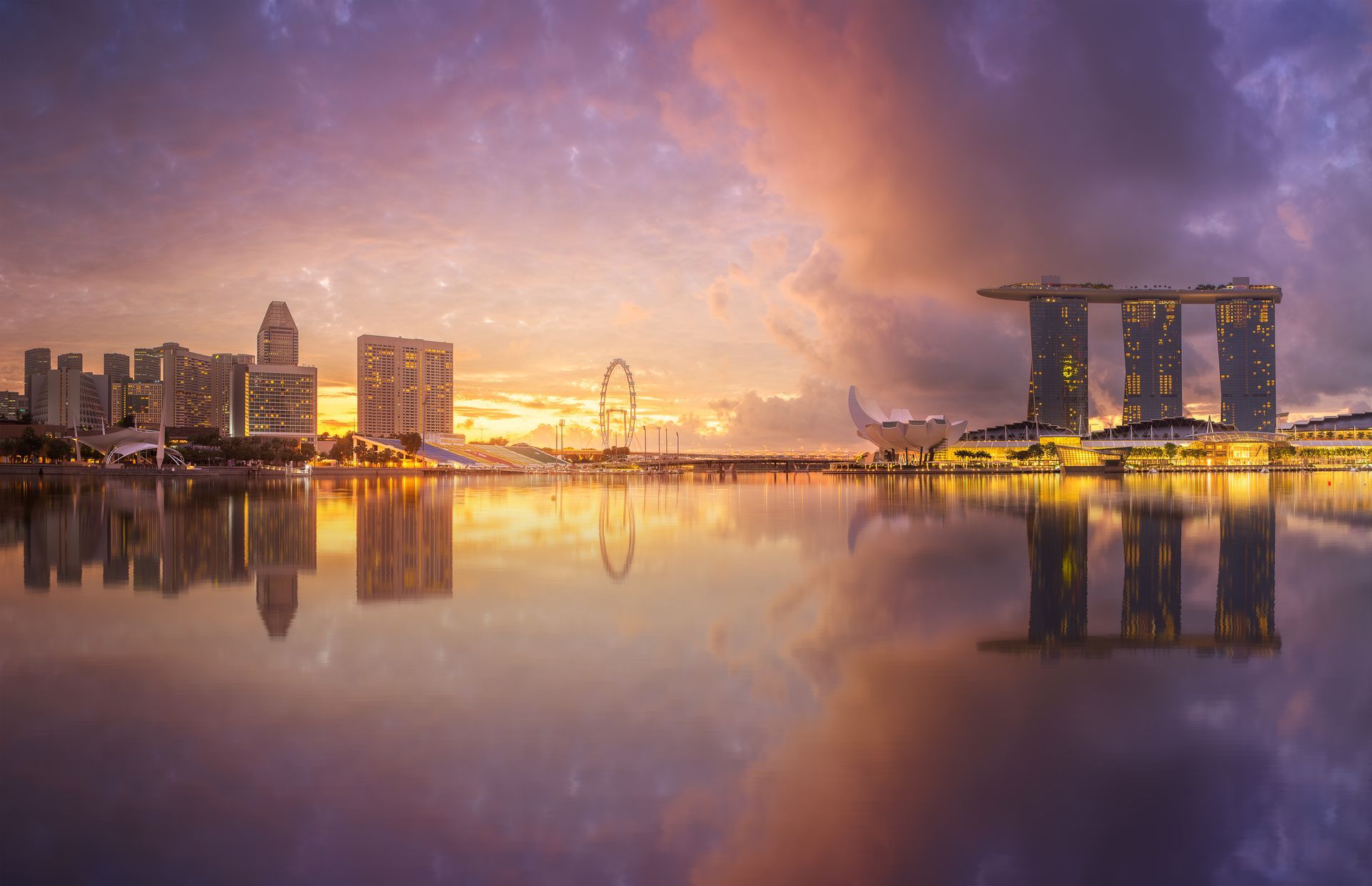 Singapore skyline at sunset, with iconic Marina Bay Sands hotel reflecting in the water.