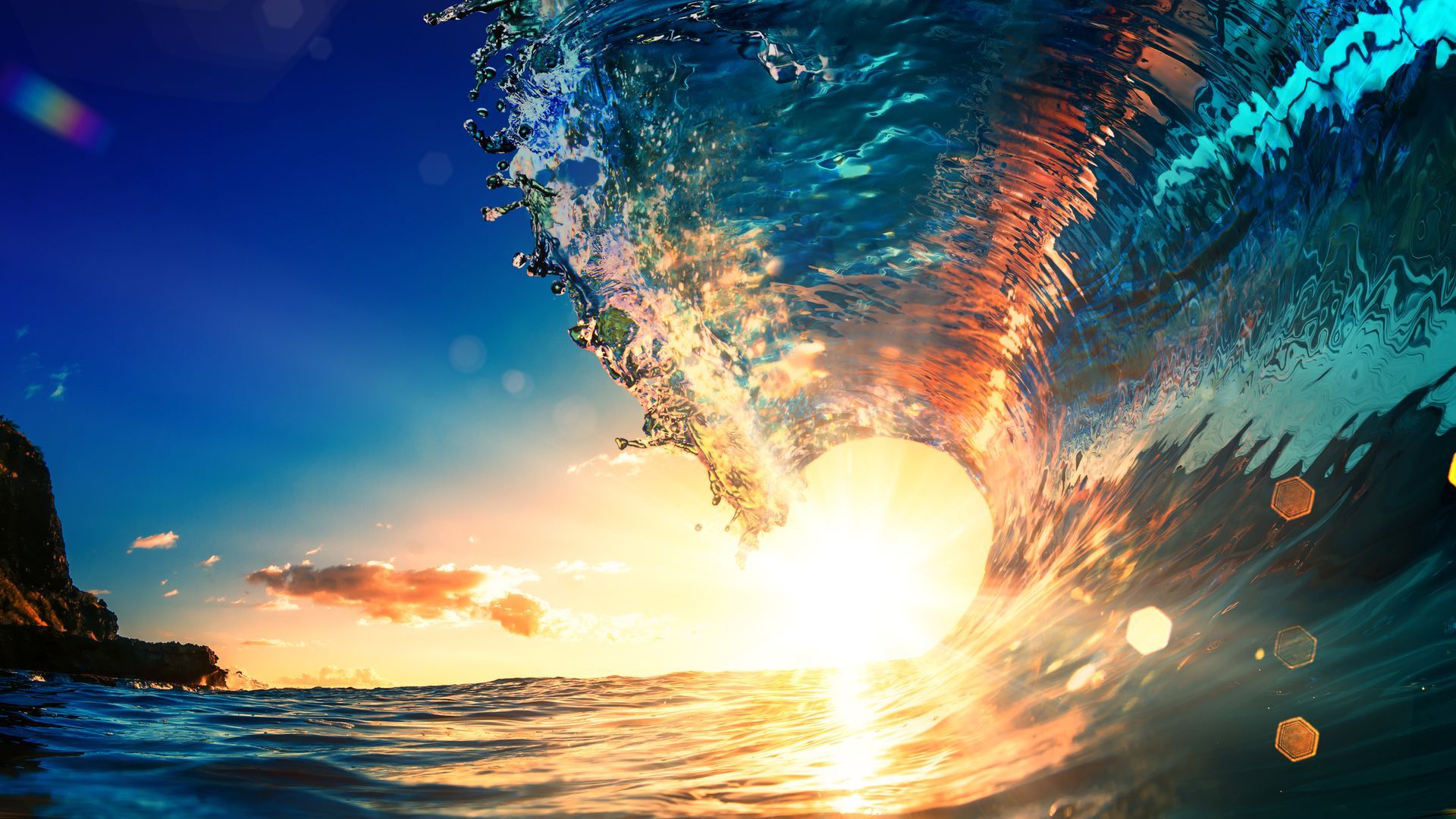 Sunset through a wave, with blue sky and golden light reflecting on the water.
