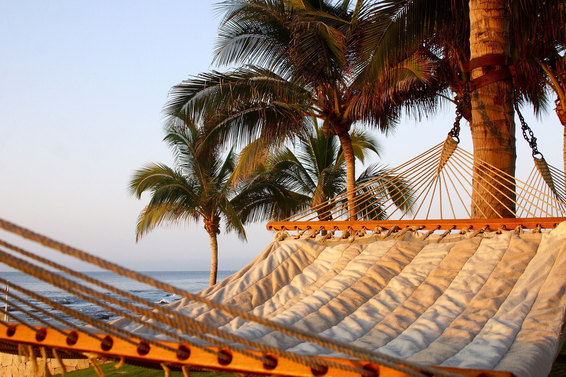Hammock under palm trees by the ocean — tropical beach relaxation on Mexico’s Riviera Maya.