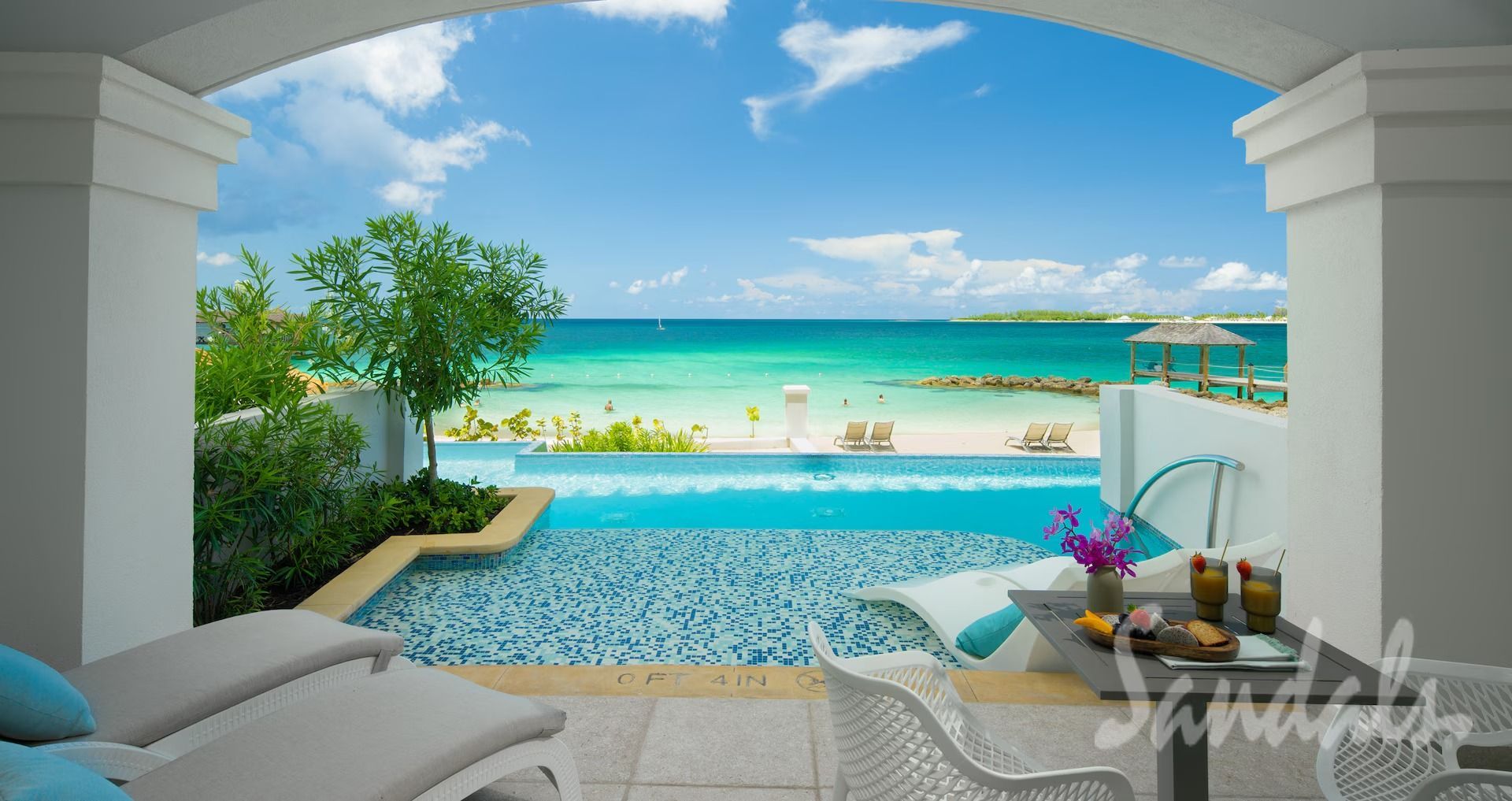 Poolside beach view with turquoise water, loungers, and drinks at Sandals resort.