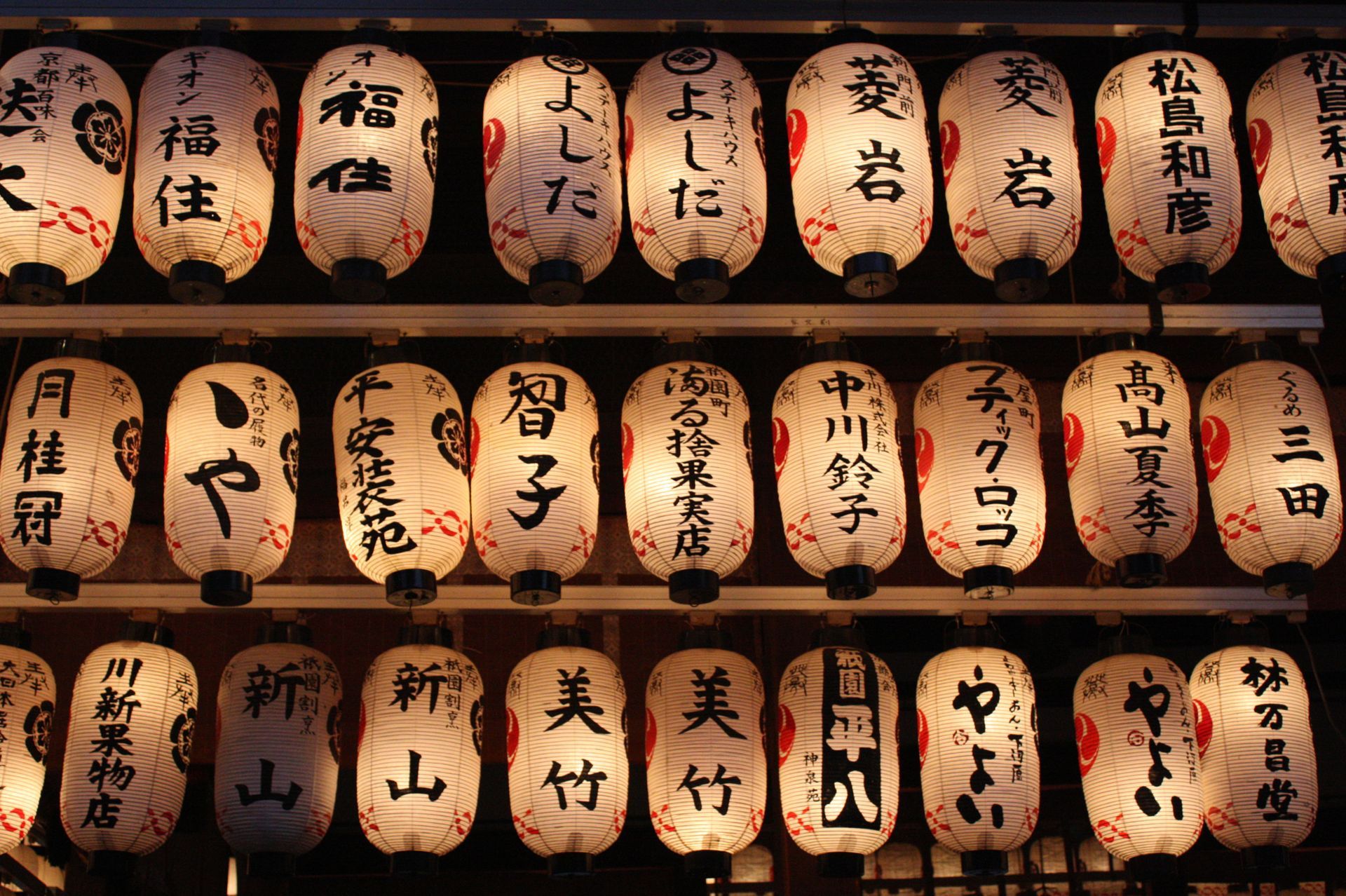 Rows of illuminated Japanese paper lanterns with black calligraphy.