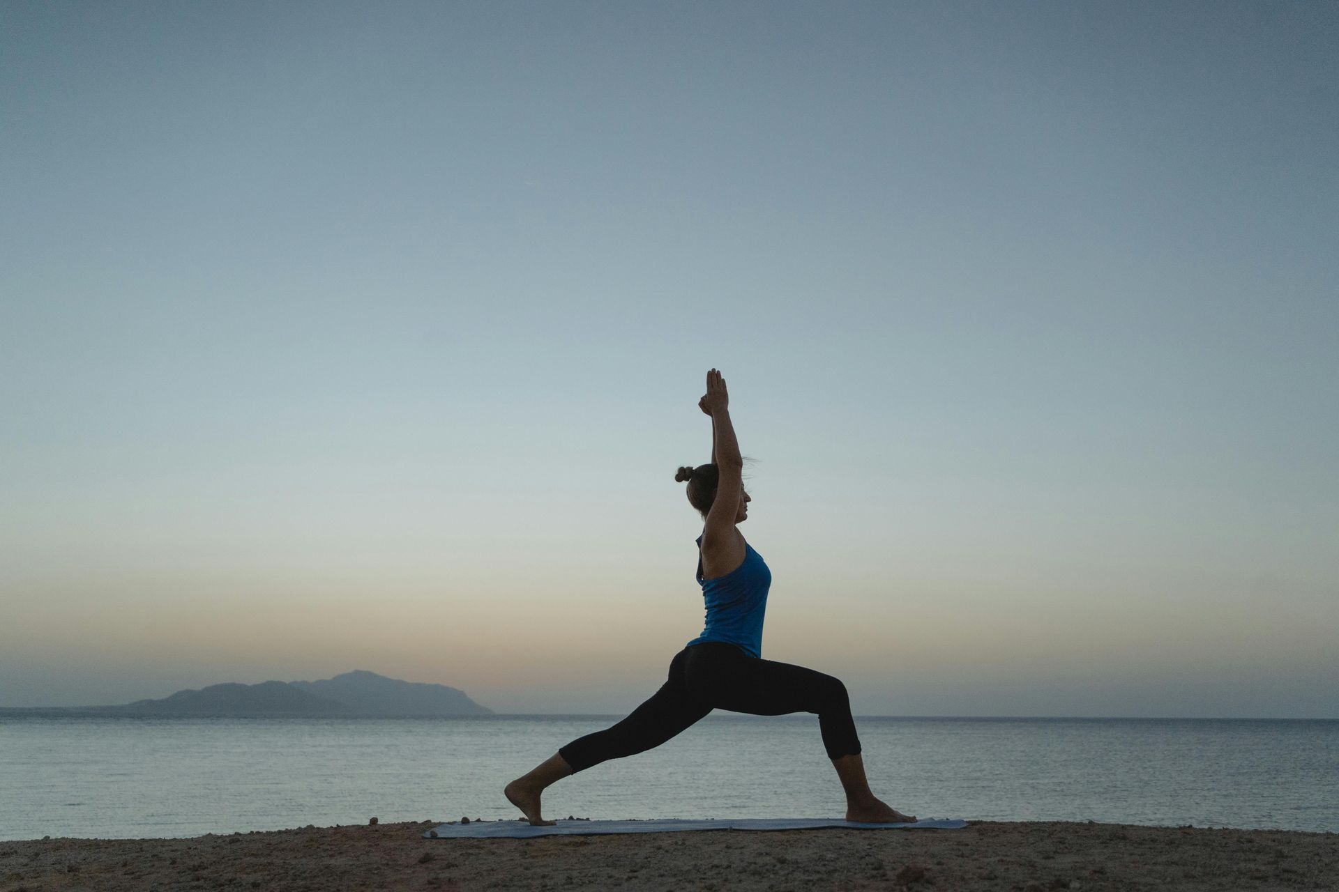 Curly-hair woman practices warrior 1 pose yoga for divorce.