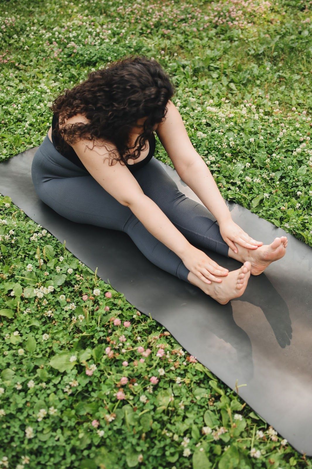 Curly-hair woman practices forward fold yoga for divorce.
