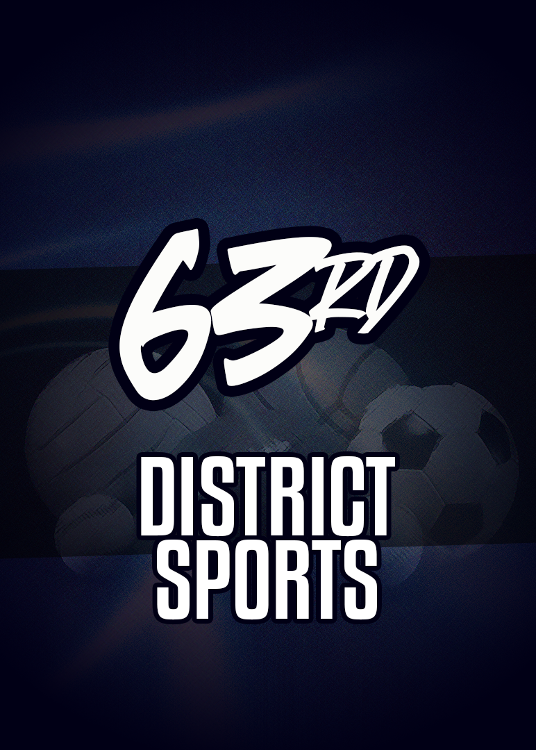 Basketball player in a blue and gold jersey dribbles the ball, eyes focused, during a game. Audience visible in the background.