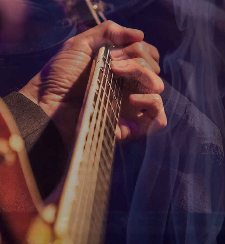 Football player in red reaching for a pass, pursued by a player in white, both on a field at night.