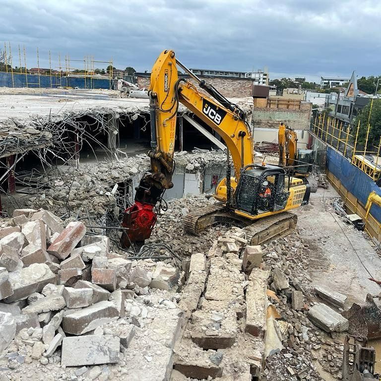 A Large Yellow Excavator Is Demolishing a Building — RC Civil in Armidale, NSW